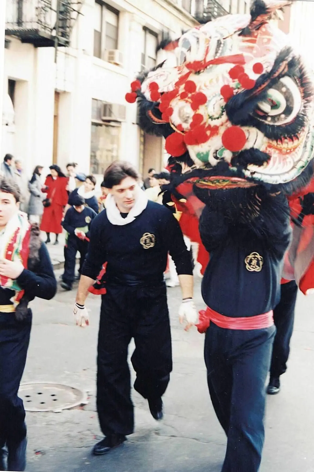 A Lion Dance team carrying a large red, white, and black lion through Chinatown