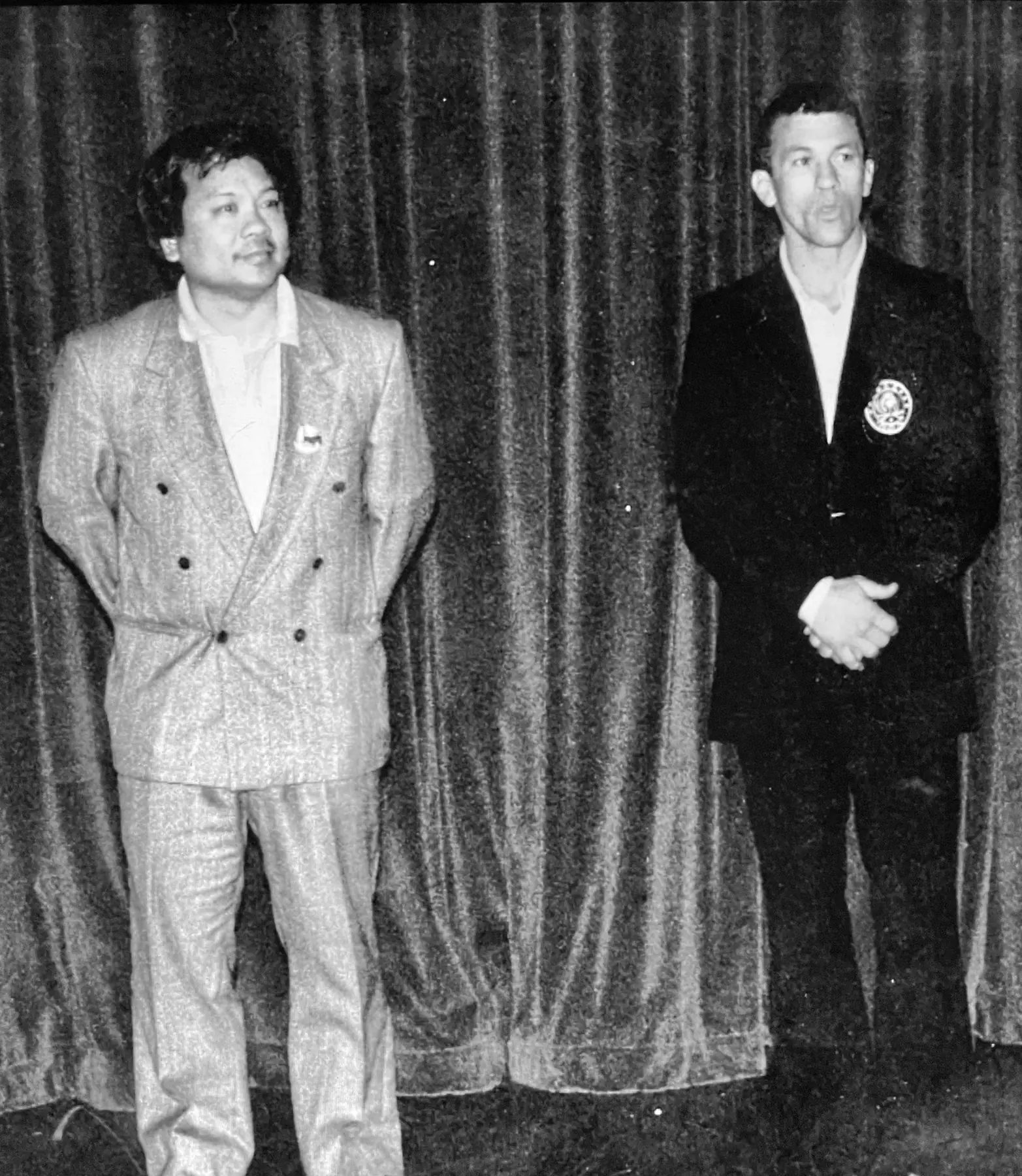 Sifu Tony Lau and Paul Vizzio standing together before a stage curtain in 1992